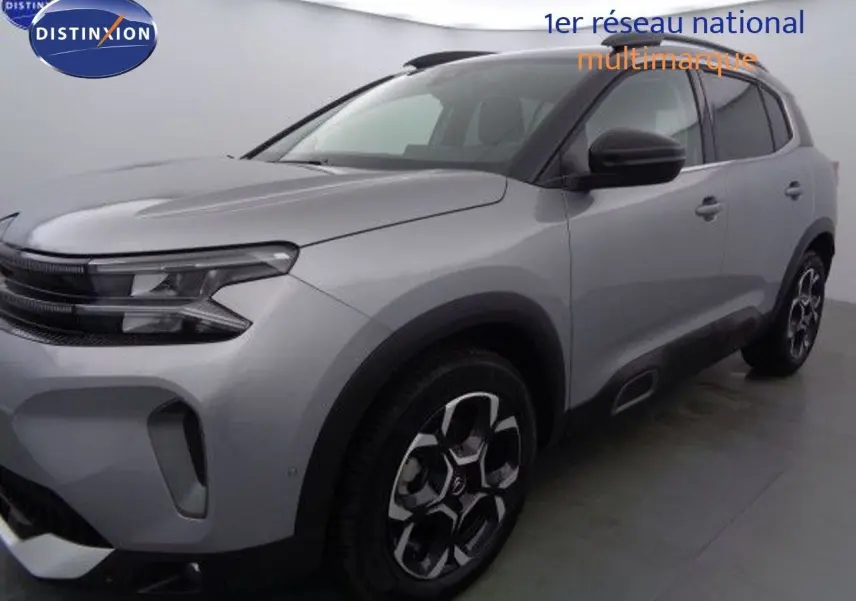 Vue 3/4 avant droit d'un Citroën C5 Aircross gris Artense métallisé avec jantes bi-ton et toit noir contrasté.