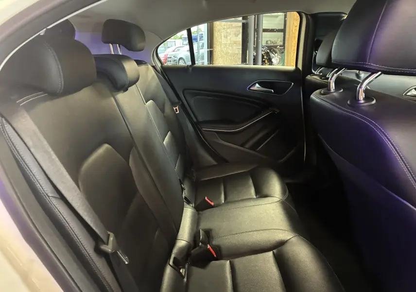 Vue intérieure côté droit des sièges arrière en cuir noir d'une Mercedes Classe A 200D blanche de 2016.