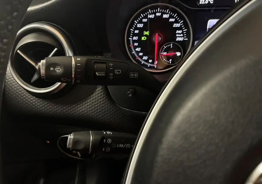 Gros plan sur le tableau de bord et les commandes au volant d'une Mercedes Classe A 200D 2016 avec affichage du compteur et ventilation.