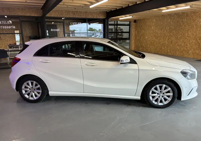 Profil droit d'une Mercedes Classe A 200D blanche de 2016, compacte et élégante, stationnée en intérieur.