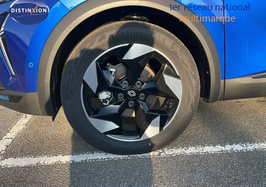 Gros plan sur la roue avant gauche du Renault Captur bleu Iron Metal avec jante noire et grise design moderne.