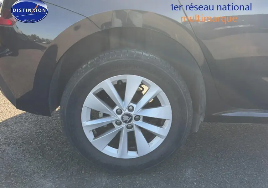 Gros plan sur la roue arrière droite d'un Skoda Kamiq noir avec jante alu et logo Skoda visible.