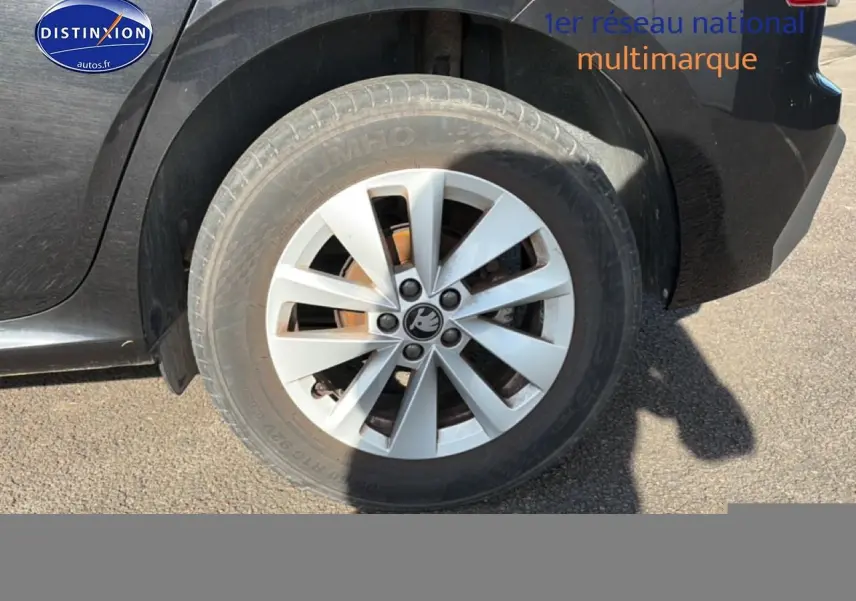 Gros plan sur la roue arrière droite d'une Skoda Kamiq noire avec jante alu et logo Skoda visible.