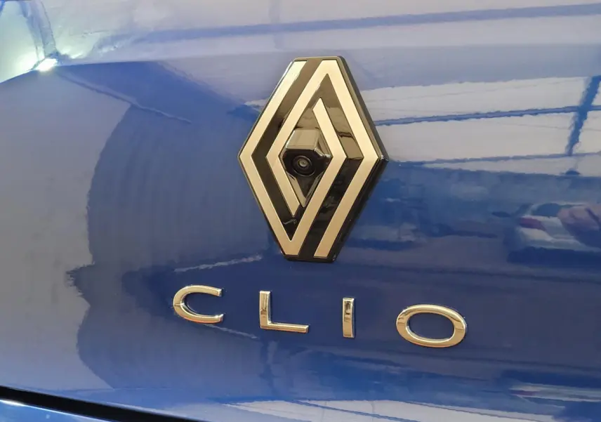 Gros plan sur le logo Renault et l’inscription Clio sur la malle arrière d’une Renault Clio bleu brillant.