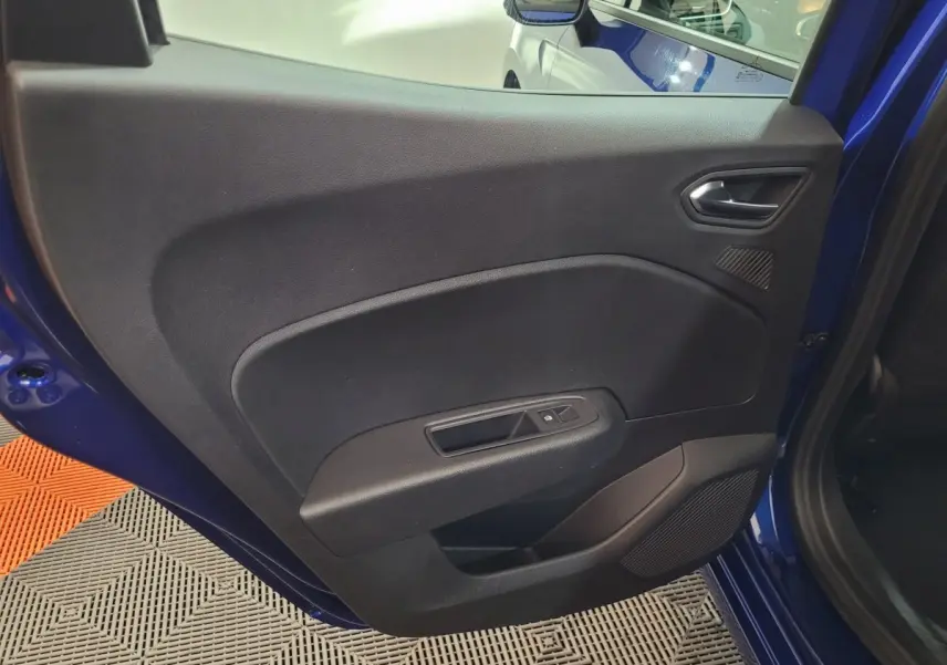 Vue rapprochée de la porte arrière gauche bleu foncé d’une Renault Clio 2025 avec commande de fenêtre et haut-parleur intégré.
