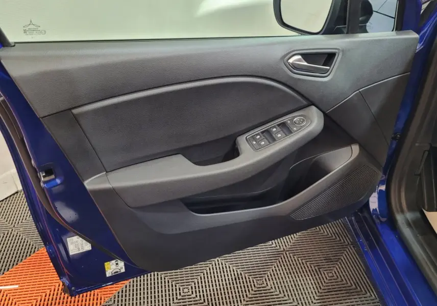 Vue rapprochée de la porte avant gauche bleu Renault Clio 2025, avec commandes électriques et haut-parleur intégré.