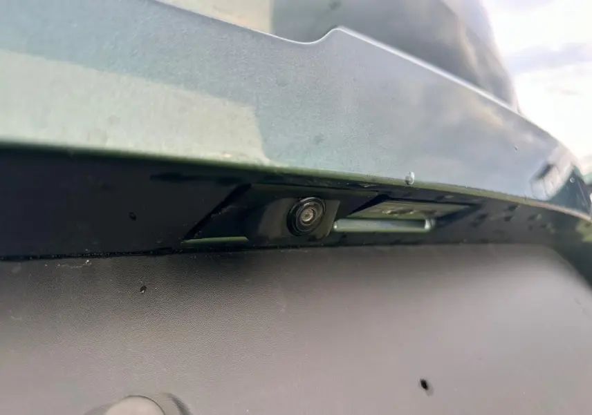 Gros plan sur la caméra de recul intégrée au pare-chocs arrière du Dacia Sandero III Stepway vert cèdre.