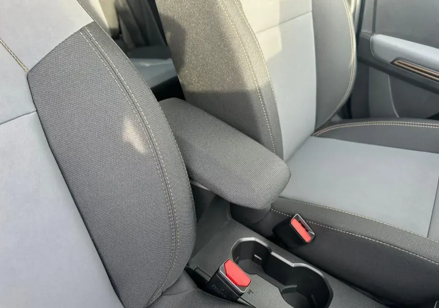 Gros plan sur l'accoudoir central et les sièges avant gris foncé avec surpiqûres contrastantes du Dacia Sandero Stepway 2025.
