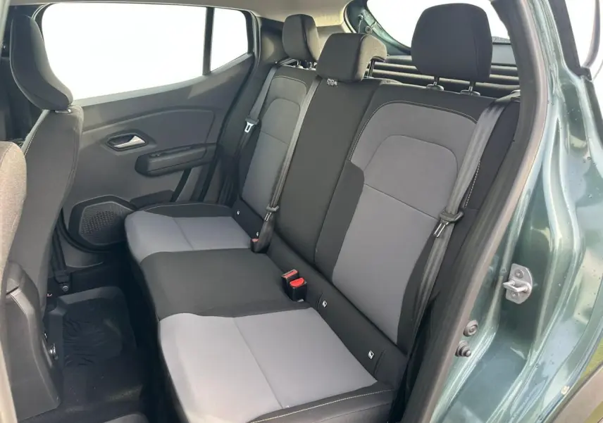 Vue côté droit de la banquette arrière bi-ton gris et noir du Dacia Sandero III Stepway vert cèdre avec porte ouverte.