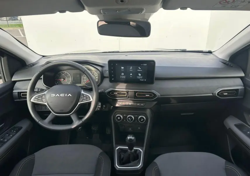 Vue intérieure avant du tableau de bord et volant noir de la Dacia Sandero III Stepway avec écran tactile central.