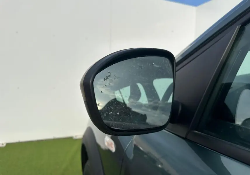Rétroviseur droit de la Dacia Sandero III Stepway vert cèdre, avec détecteur d'angle mort visible.