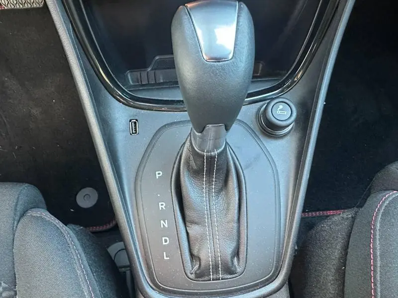 Gros plan sur le levier de vitesse automatique noir avec coutures blanches dans l'habitacle du Ford Puma gris.