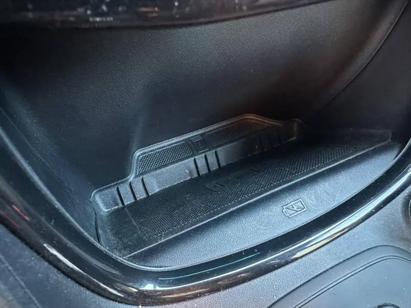 Gros plan sur le compartiment de rangement intérieur noir du Ford Puma 2024, avec surface antidérapante et symbole de charge sans fil.