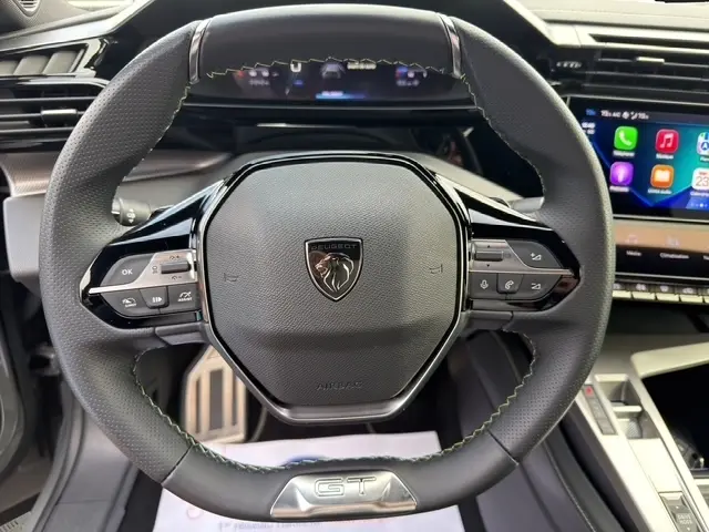 Vue rapprochée du volant cuir noir avec logo Peugeot et badge GT du Peugeot 408 Hybrid 145 e-DCS6 GT 2025.