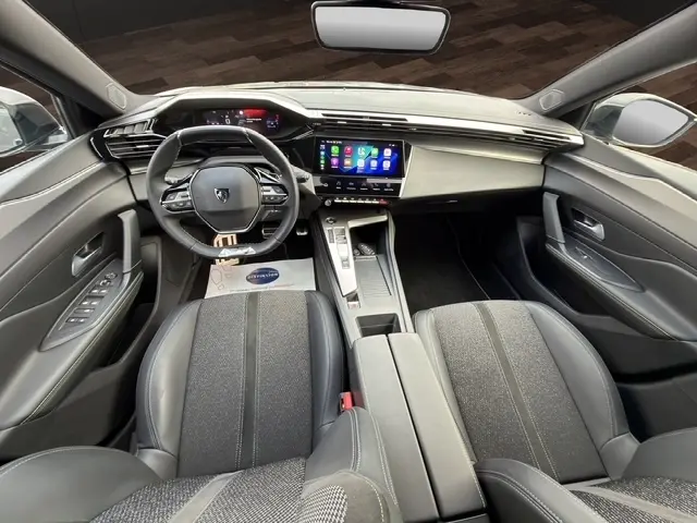 Vue intérieure avant du Peugeot 408 Hybrid gris clair, avec tableau de bord numérique et écran tactile central lumineux.