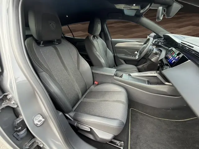 Vue intérieure côté conducteur du Peugeot 408 Hybrid gris clair, avec sièges en cuir et tableau de bord numérique.