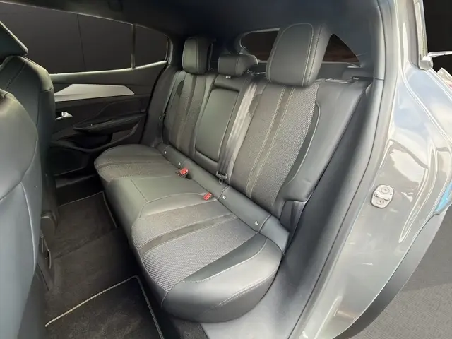 Vue intérieure côté droit sur la banquette arrière gris clair en cuir et tissu du Peugeot 408 Hybrid 145 e-DCS6 GT 2025.
