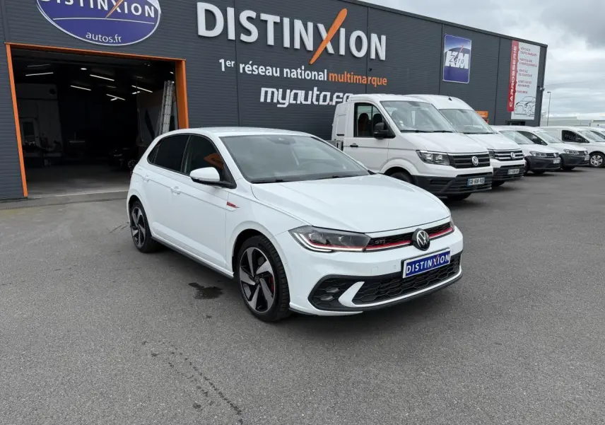 Volkswagen Polo GTI blanc pur vue 3/4 avant droit, avec jantes sport et calandre rouge distinctive.