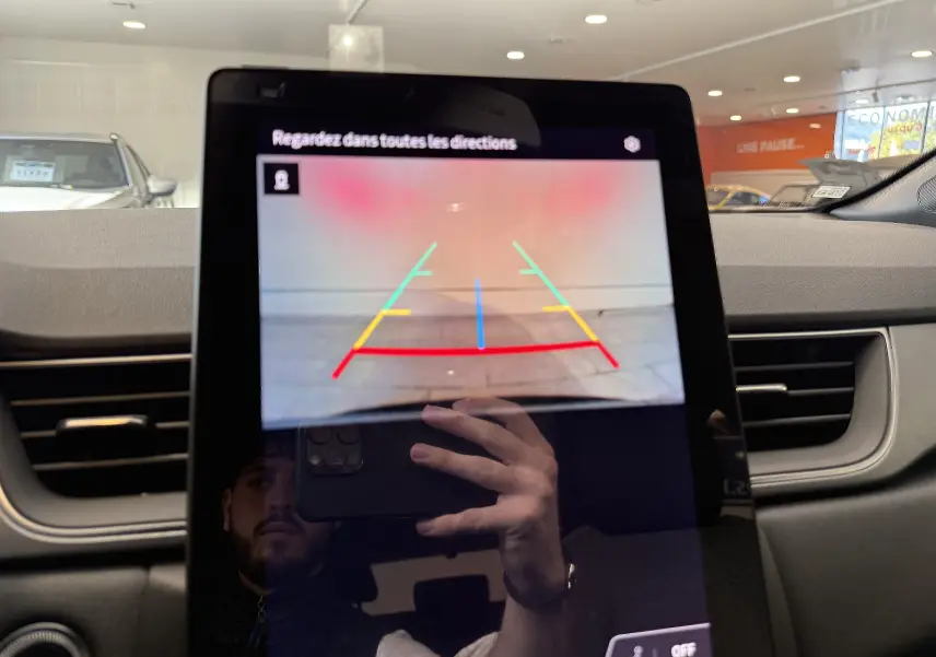 Écran central du Renault Captur 2025 montrant la caméra de recul avec lignes de guidage colorées dans un intérieur gris.