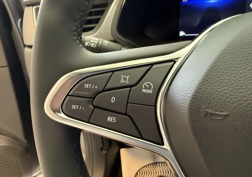 Gros plan sur les commandes de régulateur de vitesse au volant cuir noir du Renault Captur gris Cassiopée 2025.