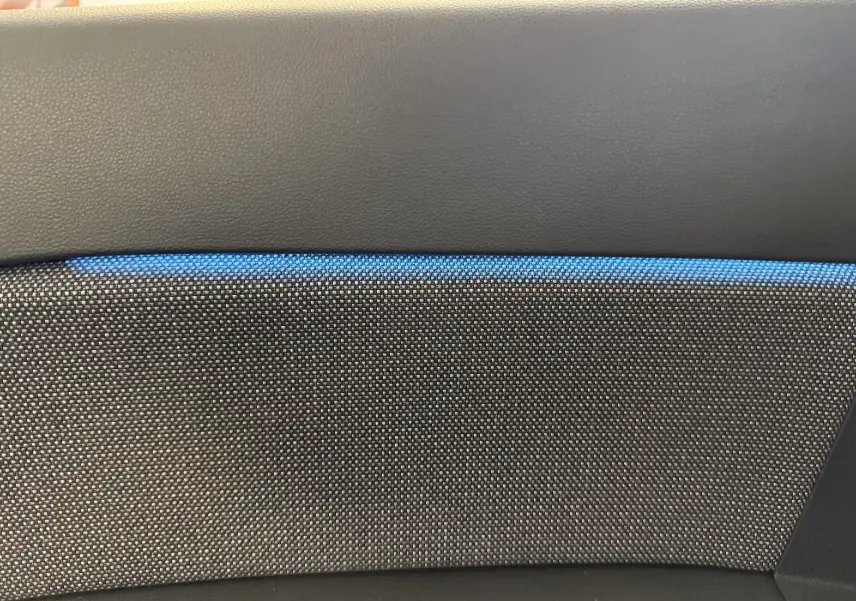 Détail du revêtement intérieur gris texturé avec bande décorative bleue du Renault Captur 2025 hybride.