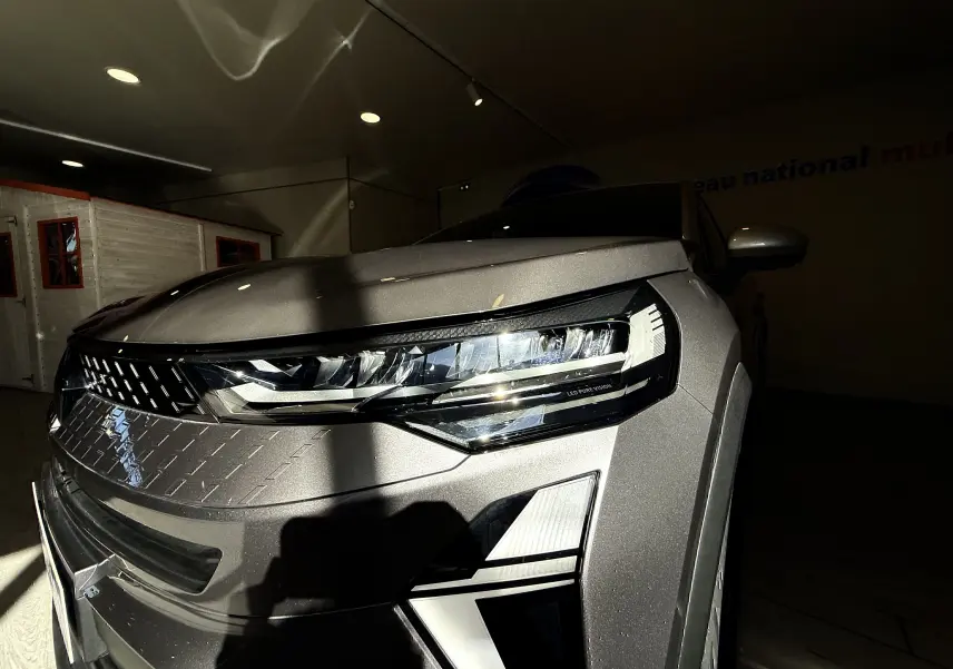 Gros plan sur l'avant droit du Renault Captur gris Cassiopée métal, mettant en valeur le phare LED et la calandre texturée.