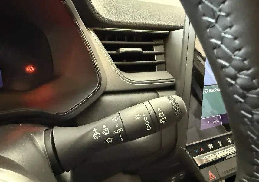 Gros plan sur la commande des essuie-glaces à gauche du volant dans l'habitacle gris du Renault Captur 2025.