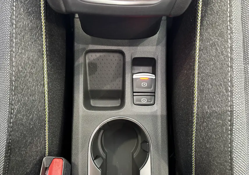 Vue rapprochée de la console centrale du Renault Captur 2025, avec surpiqûres jaunes et boutons de frein électronique.