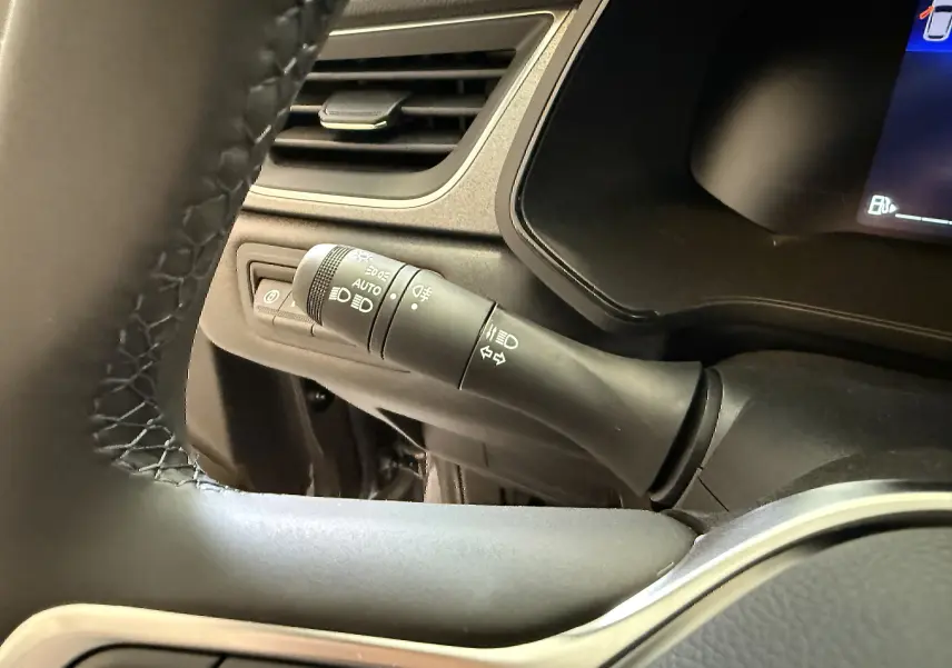 Gros plan sur la manette des feux et clignotants côté gauche du volant dans un Renault Captur gris Cassiopée 2025.
