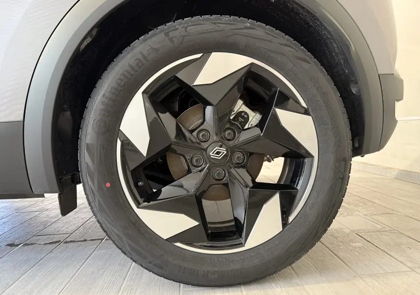 Gros plan sur la roue avant gauche du Renault Captur 2025 gris Cassiopée, jante noire et argentée au design géométrique.