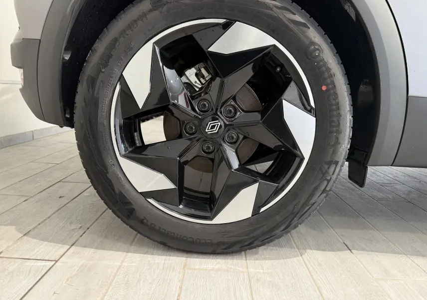 Gros plan sur la roue avant droite du Renault Captur gris Cassiopée, avec jante noire et argentée au design étoilé.