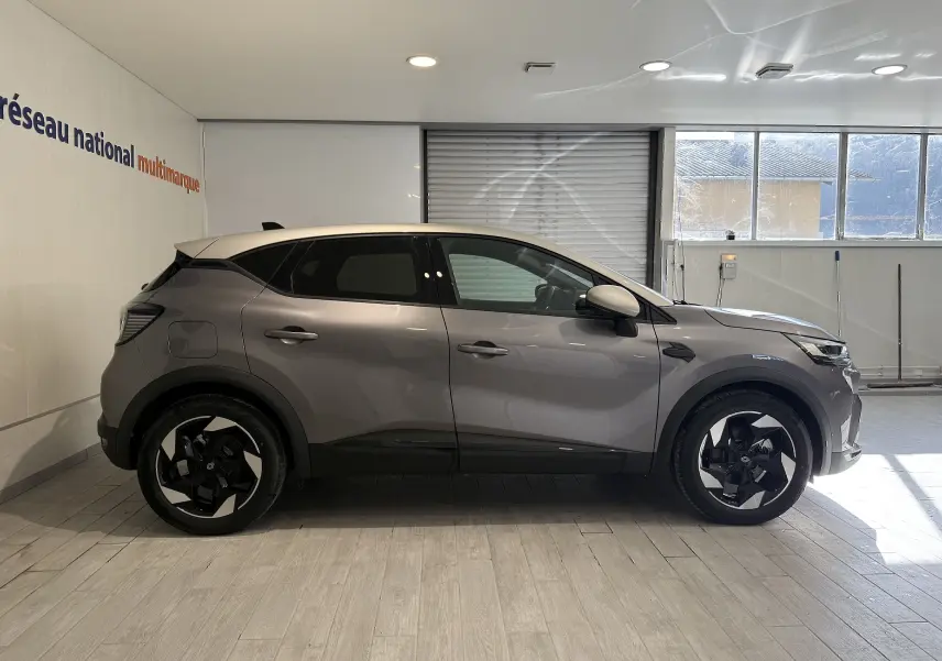 Profil droit du Renault Captur 2025 gris Cassiopée métal avec toit gris, jantes noires et vitres teintées.