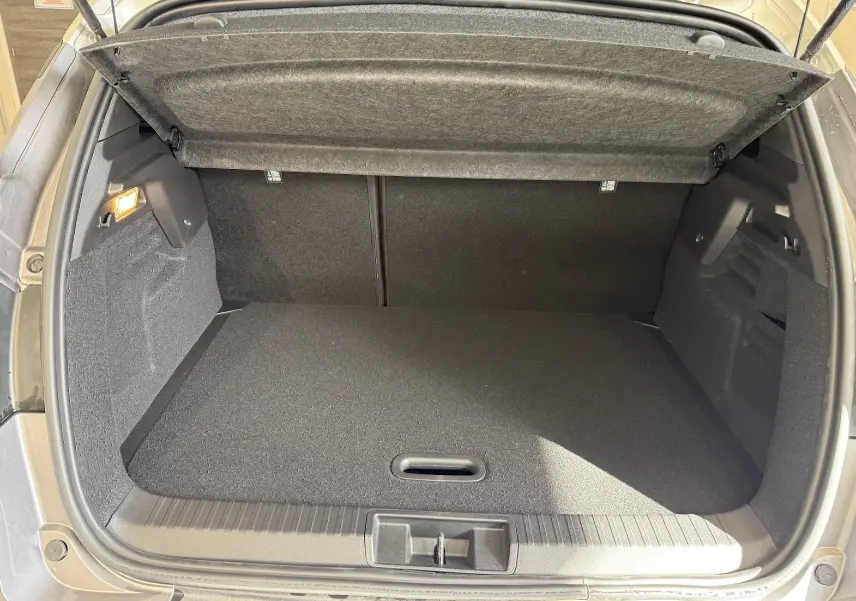 Coffre ouvert vu de l'arrière d'un Renault Captur gris Cassiopée métal avec intérieur noir et cache-bagages relevé.