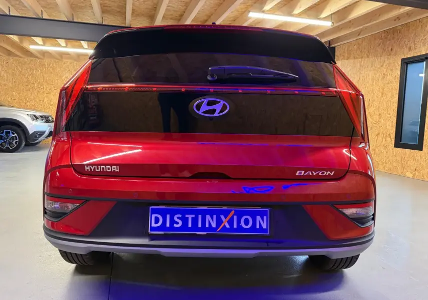 Vue arrière d'un Hyundai Bayon rouge avec calandre noir laqué et feux arrière LED dans un garage.