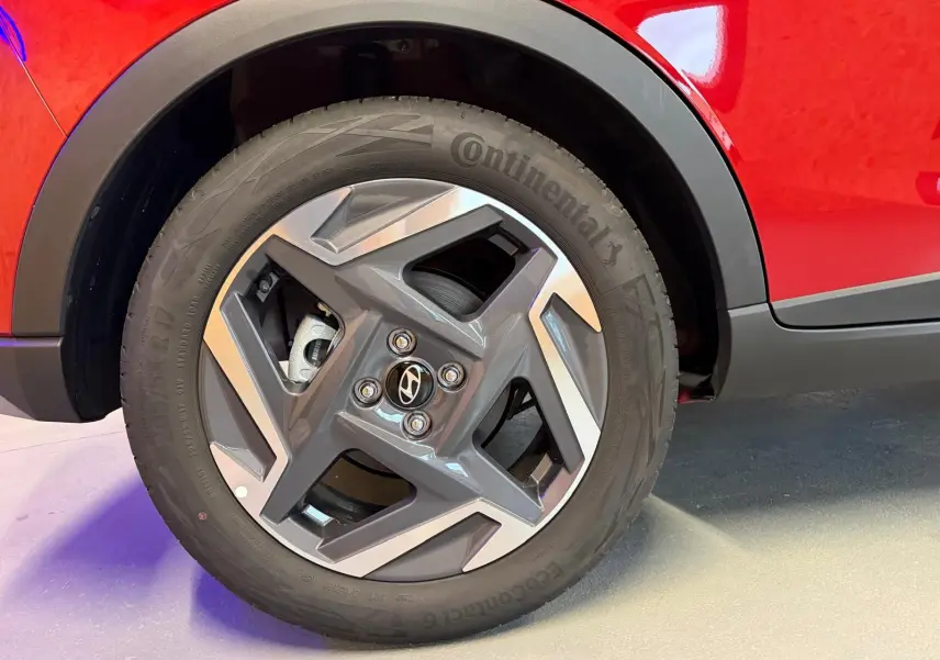 Gros plan sur la jante alu 17'' et le passage de roue noir d'une Hyundai Bayon rouge côté arrière droit.
