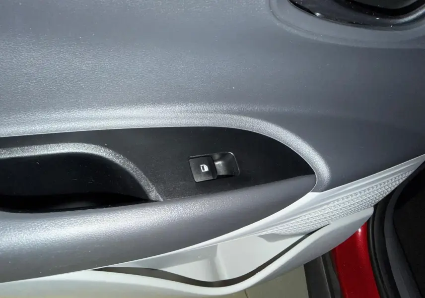 Gros plan sur la commande de verrouillage de porte côté gauche dans l'habitacle bi-ton noir et gris clair du Hyundai Bayon rouge.