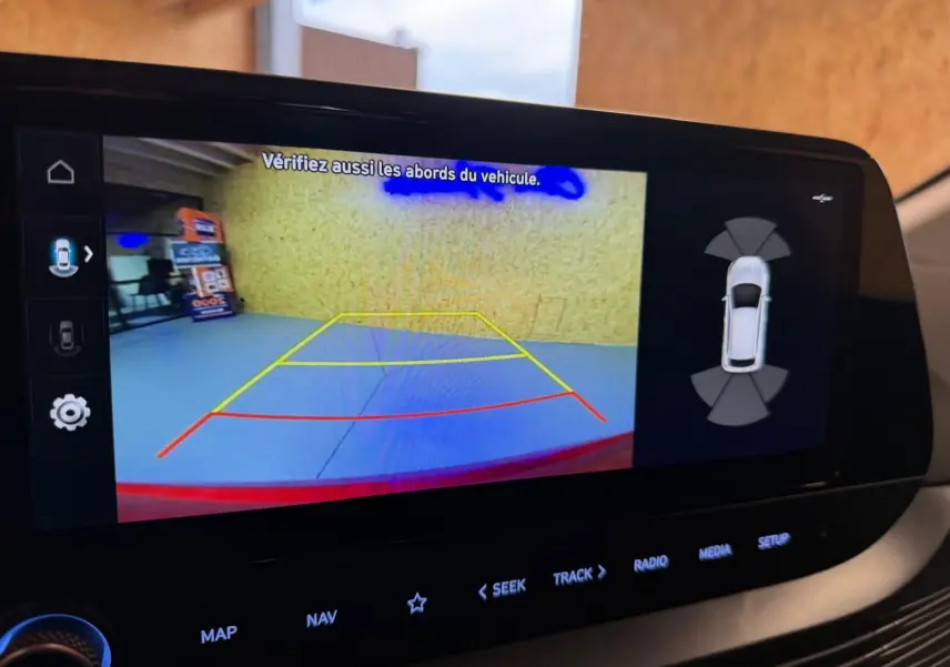 Écran tactile intérieur montrant la caméra de recul et l'aide au stationnement du Hyundai Bayon rouge 2025.
