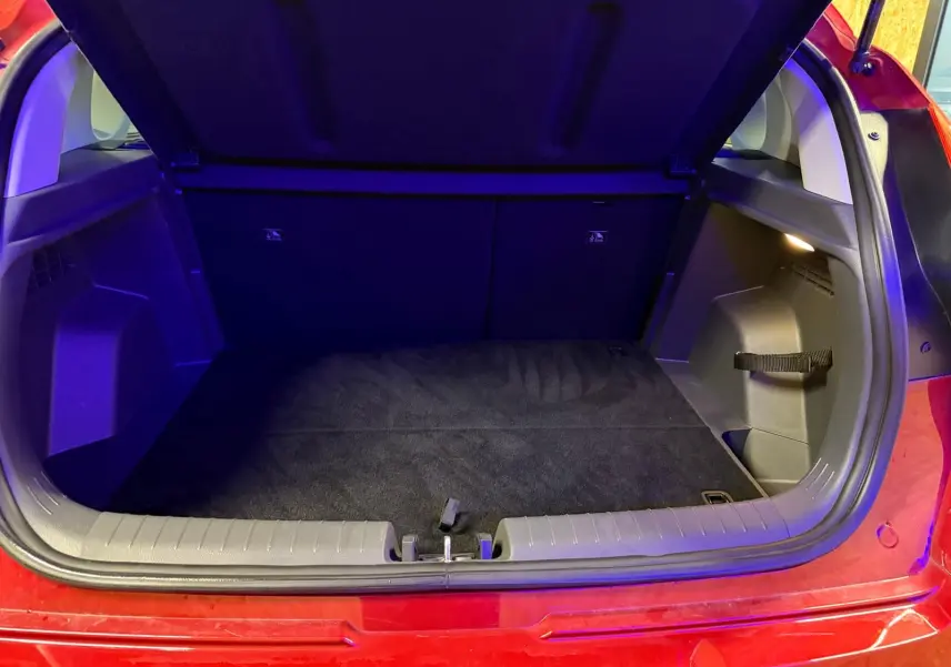 Coffre ouvert vu de l'arrière d'une Hyundai Bayon rouge 2025, espace de chargement propre et éclairé.