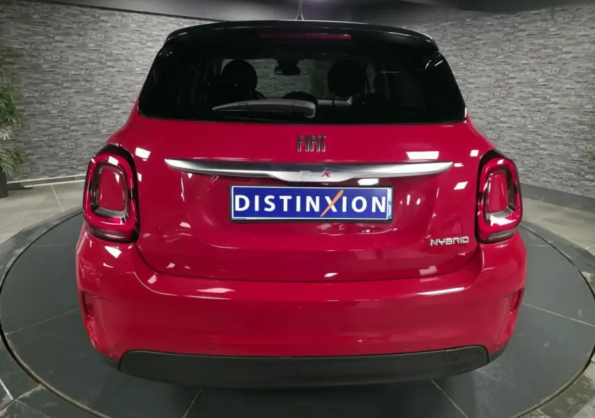 Vue arrière d'une Fiat 500X rouge Passion avec toit noir et badges Hybrid, dans un showroom intérieur.