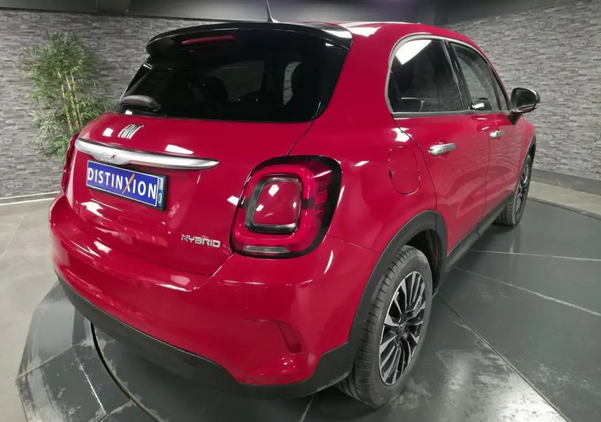 Vue 3/4 arrière droite d'une Fiat 500X rouge Passion avec jantes alliage 17'' et vitres surteintées.