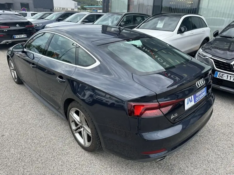 Audi A5 Sportback bleu lunaire métal vue 3/4 arrière droit, mettant en valeur ses lignes fluides et feux LED distinctifs.