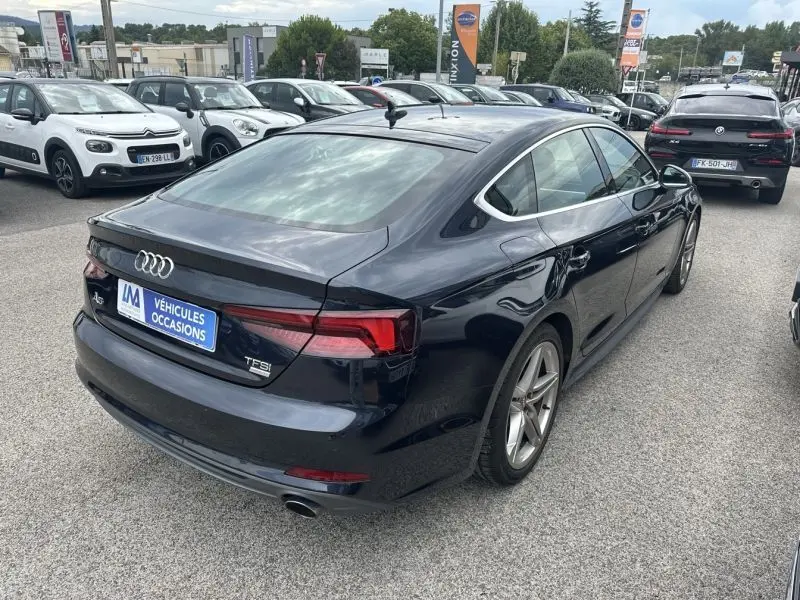 Audi A5 Sportback bleu lunaire métal vue 3/4 arrière droit, avec feux LED et jantes alliage 18 pouces visibles