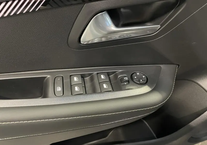 Détail de la commande des vitres et rétroviseurs côté gauche intérieur d'une Peugeot 208 noire métallisée.