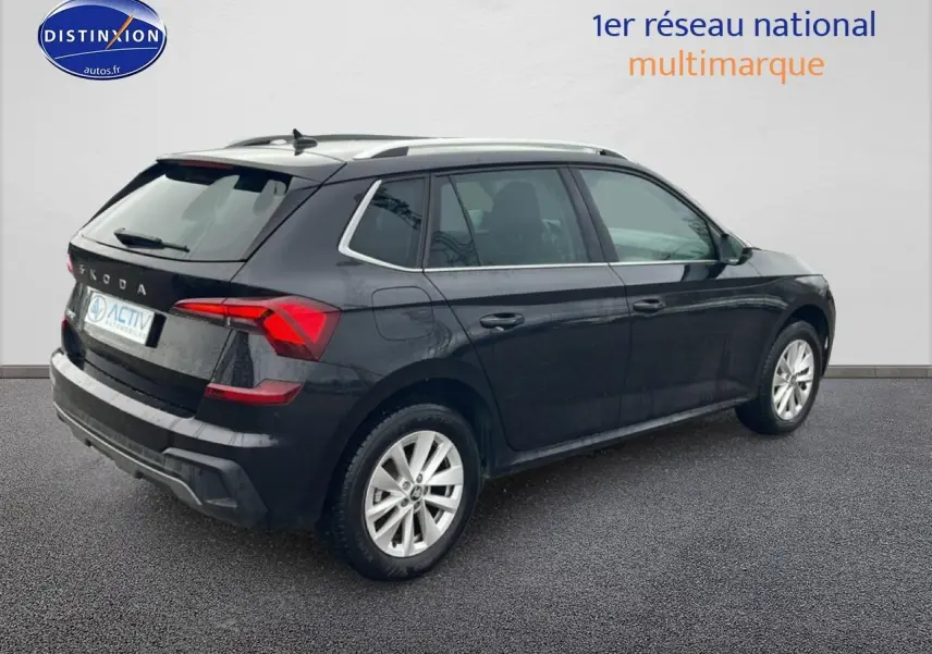 Vue 3/4 arrière droite d'un Skoda Kamiq noir avec jantes alu et barres de toit visibles.