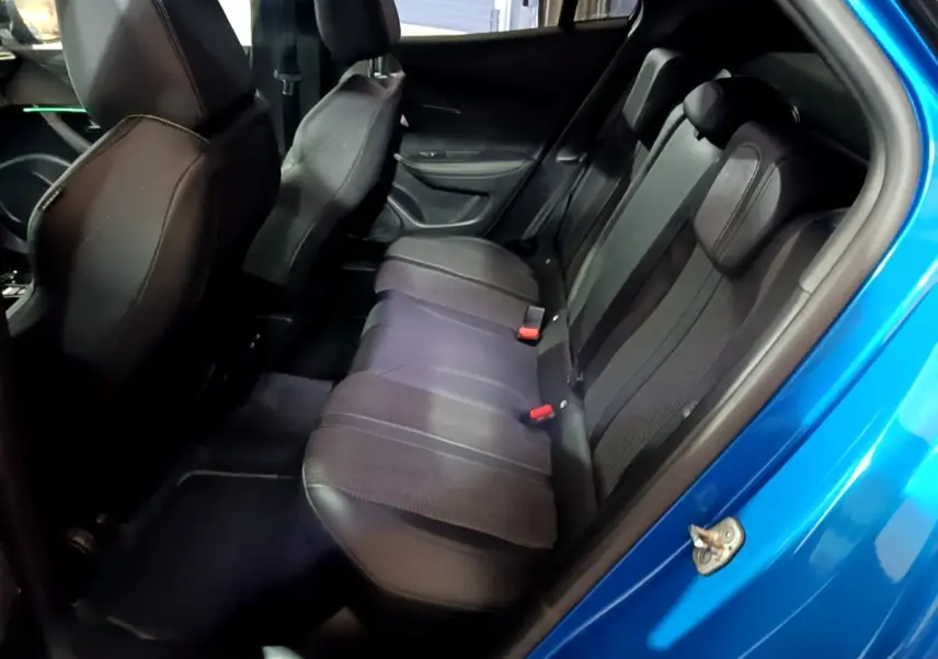 Vue intérieure côté droit sur la banquette arrière en cuir noir du Peugeot 2008 bleu, avec porte ouverte.