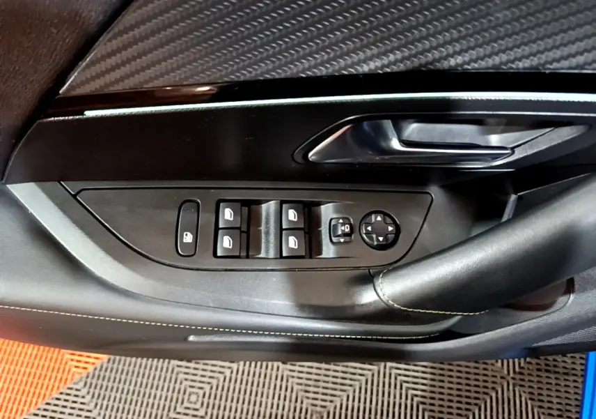 Gros plan sur la commande des vitres et rétroviseurs côté conducteur d’un Peugeot 2008 bleu, finition GT.