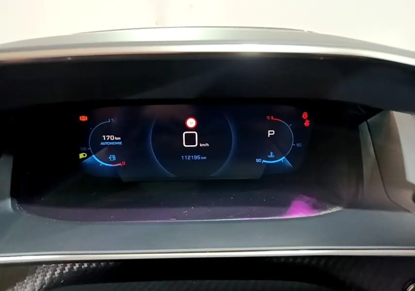 Vue rapprochée du tableau de bord numérique du Peugeot 2008 Bleu, affichant l'autonomie et la vitesse à l'arrêt.