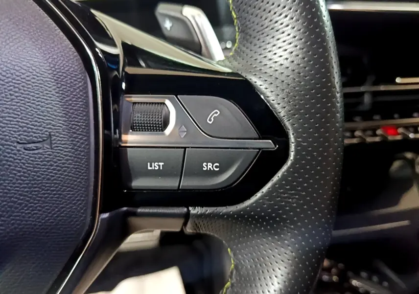 Gros plan sur les commandes gauche du volant cuir perforé du Peugeot 2008 Bleu, avec boutons LIST et SRC visibles.