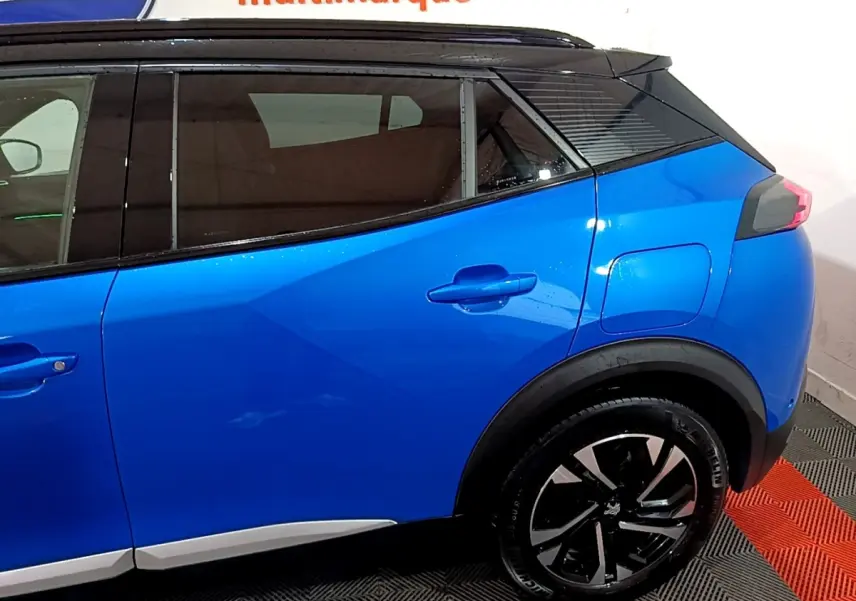 Vue latérale côté droit du Peugeot 2008 Bleu avec jantes noires et toit noir contrasté, arrière partiel visible.