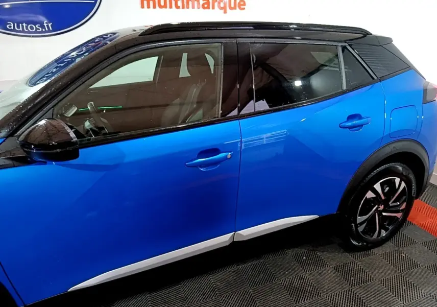 Vue latérale droite d’un Peugeot 2008 Bleu avec toit noir et jantes distinctives en alliage.